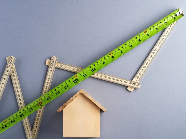 Mètres pliants et maquette de maison en bois, symboles du mesurage des surfaces