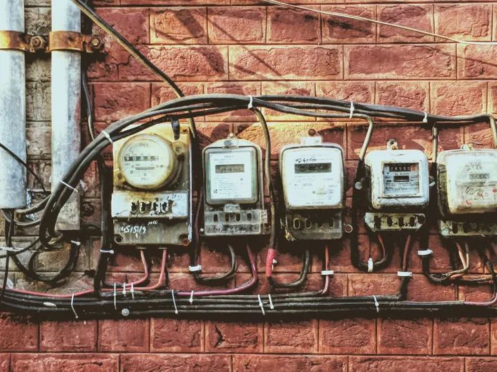 Compteurs électriques anciens fixés sur un mur de briques